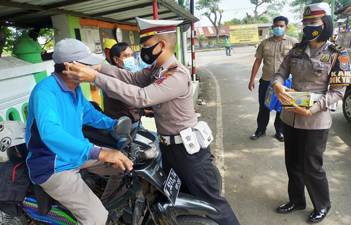 Petugas saat memasang masker pada tukang ojek di Blawi.