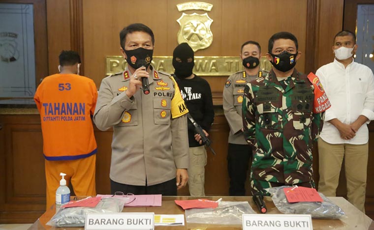 Kapolda Jatim, Irjen Pol Dr Nico Afint (pegang mik) saat memberikan keterangan pers di Mapolda Jawa Timur, Sabtu (5/12/2020) pukul 20.00 WIB. Tampak juga Aji Dores, warga Pamekasan, Madura yang mengancam akan membunuh Menko Polhukam RI, Prof. Dr. Moh. Mahfud, MD memakai baju tahanan berwarna oranye membelakangi para aparat. foto: ist/ana/ bangsaonline.com