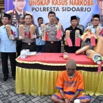 Rizky Pratama Putra (27) alias Kiko dan barang bukt ganja yang disita polisi. foto: Catur Andy Erlambang/ bangsaonline.com