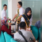 Duta Layanan Kantor Imigrasi Kediri saat memberikan makanan ringan (cemilan) dan minuman kepada pemohon Paspor. (foto: ist)