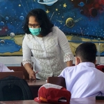 Seorang Ibu Guru saat berinteraksi dengan muridnya. Foto: Ist.