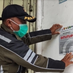 Petugas Satpol PP Kota Kediri saat menempelkan stiker pengumuman. Foto: Muji Harjita/ BANGSAONLINE.com 