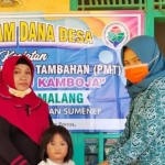 Ketua Tim Penggerak Pemberdayaan Kesejahteraan Keluarga (TP-PKK) Desa Aeng Panas, Busiyah Romli saat menyalurkan paket makanan tambahan untuk mencegah stunting secara simbolis.