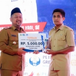 Bupati Gresik, Fandi Akhmad Yani menyerahkan hadiah kepada perwakilan desa pemenang lomba digital Nawakarsa Award Desa  SIAP. Foto: SYUHUD/BANGSAONLINE.com