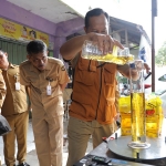 Petugas saat melakukan Uji Takar MinyaKita Kemasan 1 Liter. (Ist).