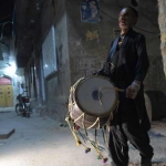 Gambar ini diambil pada 30 Mei 2018. Tampak seorang pria Pakistan Lal Hussain (C), 66, tengah menabuh drumnya untuk membangunkan warga agar makan sahur di Bani, daerah pemukiman tua, di Rawalpindi. (AFP) 