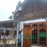 DIHAJAR BADAI: Warga bergotong royong memperbaiki atap rumahnya yang porak poranda diterjang puting beliung. foto: feri/ BANGSAONLINE