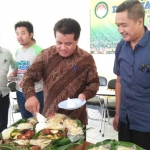 Ketua Panwaslu Jombang Nur Khasanuri (baju batik) memberikan potongan tumpeng kepada Ketua KPU Jombang Muhaimin Shofi saat tasyakuran kantor Panwaslu. 