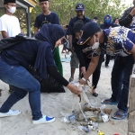 Pengurus Nasdem dan Garnita Gresik memunguti sampah dalam aksi sosial bersih-bersih Pantai Delegan. foto; SYUHUD/ BANGSAONLINE
