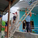 Petugas BPBD Kota Batu saat mengevakuasi atap TPS yang menimpa rumah warga.