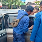 Petugas damkar unit Krian saat berupaya membuka jendela mobil. Foto: Ist.