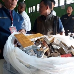 Para petugas saat melakukan penyitaan ribuan bungkus rokok serta obat-obatan dan jamu. foto: ist