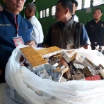 Para petugas saat melakukan penyitaan ribuan bungkus rokok serta obat-obatan dan jamu. foto: ist