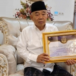 Prof Dr KH Asep Saifuddin Chalim, MA, memegang sertifikat penghargaan The Most Boarding Islamic School in Education Quality Exellence of the Year di kediamannya di Jalan Siwalankerto Utara Surabaya, Jumat (21/3/2025). Foto: MMA/bangsaonline