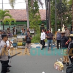 LSM MDW saat unjuk rasa sambil menghamburkan uang dan menyerahkan obat tolak masuk angin di depan Kasatreskrim Polres Sampang. Foto: MUTAMMIM/ BANGSAONLINE