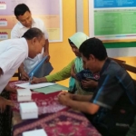 Suhardi, Komisioner KPU Pacitan Divisi Sosialisasi, SDM, dan Partisipasi Masyarakat saat berbincang dengan pemilih penyandang disabilitas. foto: Yuniardi Sutondo/ bangsaonline.com