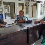 Dengan jarak lebih dari 1 meter, pegawai Disperindag Mojokerto memberi arahan kepada kepala desa mengenai ditundanya sosialisasi Tera bagi masing-masing PKK di setiap desa.