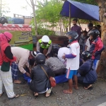 Polisi dan masyarakat sedang menolong korban.