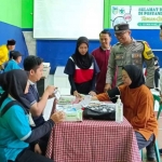 Bhabinkamtibmas Sidomulyo, Aipda Himawan Pratama, saat ikut memantau pemeriksaan kesehatan. Foto: Ist