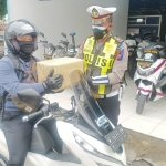Petugas Satlantas Polres Gresik memberikan paket sembako kepada pengguna jalan yang tertib berlalu lintas. foto: SYUHUD/BANGSAONLINE