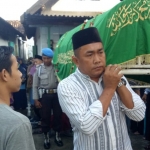 Aiptu Mohammad Zakfar (belakang) sedang membantu mengangkat jenazah menuu ke lokasi pemakaman.