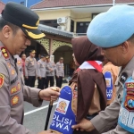 Kapolres Tanjung Perak saat memasangkan atribut kepada salah satu pelajar.