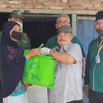 Ketua DPC PKB Madiun Muhtarom (tengah pakai topi) saat membagian paket kebutuhan pokok pada salah satu warga yang terdampak Covid-19.