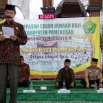 Pj Bupati secara simbolis memasangkan seragam untuk calon jemaah haji Pamekasan.