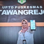Salah satu pegawai UPTD Puskesmas Tawangrejo saat menunjukkan aplikasi Mobile JKN. (Ist)