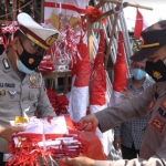 Anggota Polres Gresik saat membawa bendera merah putih yang diborong dari pedagang di Jalan Dr. Wahidin, S.H. foto: SYUHUD/ BANGSAONLINE