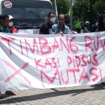 Spanduk yang dipajang di depan truk saat demo digelar di depan Kantor Kejari Madiun, Kamis (9/3/2023). Foto : Hendro Suhartono/BANGSAONLINE.com
