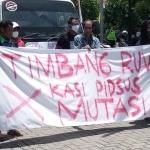 Spanduk yang dipajang di depan truk saat demo digelar di depan Kantor Kejari Madiun, Kamis (9/3/2023). Foto : Hendro Suhartono/BANGSAONLINE.com
