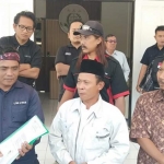 Ketua AMPTN Desa Kedamean Nur Qomari (tengah) memberikan keterangan usai melaporkan mantan Kades Kedamean ke Kejari Gresik. foto: SYUHUD/ BANGSAONLINE