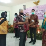 Kadinsos M Alwi (baju batik) saat menyerahkan bayi ke salah satu orangtua asuh.