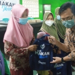 Nur Basuki menyerahkan bantuan ikan untuk dikonsumsi kepada peserta sosialisasi Gemarikan dan sekaligus sebagai pembudidaya ikan lele dalam ember.