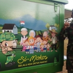Anggota Satgas TMMD berdiri di samping Simokos.