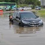 Mobil yang terjebak banjir sehingga harus didorong karena mesinnya kemasukan air, kemarin. Foto : agus HP/BANGSAONLINE