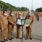 Plt Bupati Gresik Moh. Qosim didampingi Kepala Dinas LH Moh. Najikh menyerahkan piagam Adiwiyata. foto: SYUHUD/ BANGSAONLINE