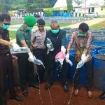 Jajaran Forpimda saat menuangkan miras ke dalam tanah galian. foto: SUWANDI/ BANGSAONLINE