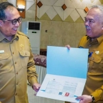 Sekdakab Gresik (kiri) dan Kepala Disperta, Eko Anindito Putro, saat penyerahan SK pensiun. Foto: Ist