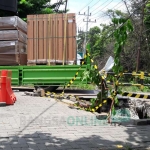 Kendaraan berat melintas di tepi jembatan yang ambrol. foto: SYUHUD/ BANGSAONLINE