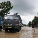 Petugas mengatur pengalihan lalu lintas akibat jalan yang tergenang banjir di Bandar Kedungmulyo, Jombang.