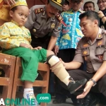Kapolres AKBP Feby Hutagalung memakaikan kaki palsu pada Rizky. foto: NUR QOMAR/ BANGSAONLINE