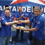 Ketua DPC Partai Demokrat Kabupaten Pasuruan M. Naufal Alghifary (kiri) menerima potongan tumpeng secara simbolis dari Ketua Dewan Pertimbangan PD H. Amir Ragil K. D.