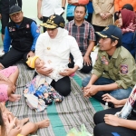 Khofifah Indar Parawansa menggendong bayi yang ikut mengungsi di Posko Kesehatan di Balai Desa Garon, Kabupaten Madiun. foto: ist