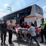 Petugas saat mengevakuasi seorang pemudik yang pingsan dari Bus Harapan Jaya rute Jombang-Mojokerto
