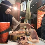 Devi, seorang pedagang daging ayam potong di Pasar Tanjung saat melayani pembeli.
