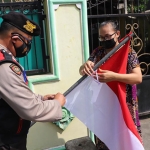 Petugas dari Polres Kediri saat membagikan bendera merah putih kepada warga dan membantu memasangkan. (foto: ist)