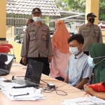 Anggota Polsek Krembung melaksanakan pengamanan terhadap masyarakat Desa Waung yang akan melaksanakan vaksinasi tahap pertama. (foto: ist)