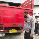 Petugas sedang menunjukkan bagian belakang truk yang ditabrak korban.